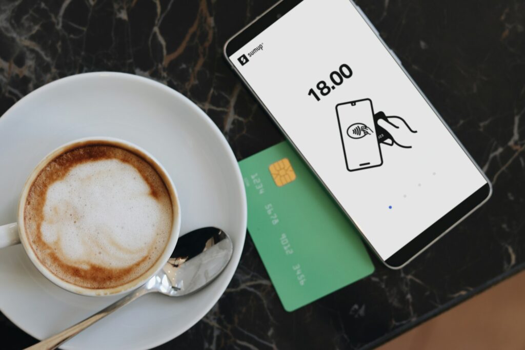 A cup of coffee on a saucer next to a credit card